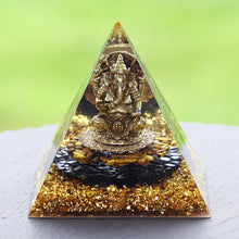 Load image into Gallery viewer, An orgonite pyramid with Tiger's Eye and Obsidian stones. Features a central metal statue of Ganesh and gold foil shavings.