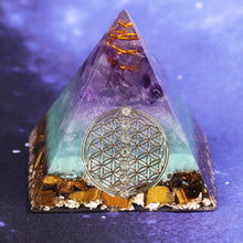 Load image into Gallery viewer, Orgonite pyramid with Tiger's Eye, Amethyst and Fluorite crystals. Includes a quartz crystal in a copper energy coil, gold foil shavings and a sacred Flower of Life energy patch.