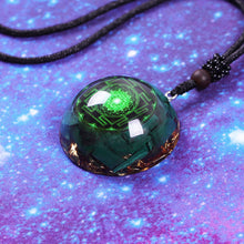 Load image into Gallery viewer, Green orgonite necklace featuring sacred geometry, crafted with malachite and copper elements, set in a domed resin pendant, displayed on a cosmic purple and blue starry background.