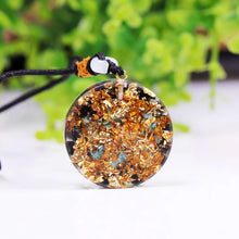 Load image into Gallery viewer, Rear view of a pendant of turquoise and obsidian orgonite necklace showing the gold foil shavings side.