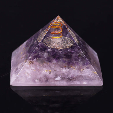 An orgonite pyramid containing natural Amethyst and Rose Quartz crystals. The top layer has an orgone energy copper coil on top of a copper energy patch.