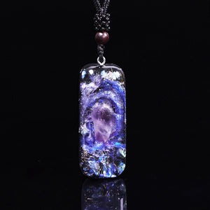 An orgonite pendant necklace with a single Amethyst crystal in the center and a marbled design that appears like a surrounding galaxy.