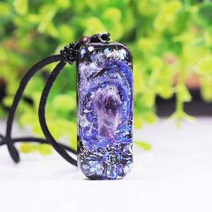 An orgonite pendant necklace with a single Amethyst crystal in the center and a marbled design that appears like a surrounding galaxy.