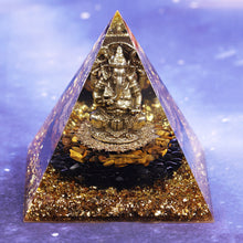 Load image into Gallery viewer, An orgonite pyramid with Tiger&#39;s Eye and Obsidian stones. Features a central metal statue of Ganesh and gold foil shavings.