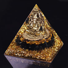 Load image into Gallery viewer, An orgonite pyramid with Tiger&#39;s Eye and Obsidian stones. Features a central metal statue of Ganesh and gold foil shavings.