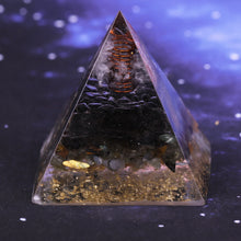 Load image into Gallery viewer, Orgonite pyramid with obsidian, labradorite and quartz crystals. Features a seven chakra copper energy patch and gold foil shavings.