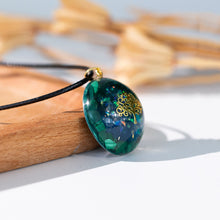 Load image into Gallery viewer, Side view of an iridescent orgonite necklace with a gold tree of life, surrounded by malachite stones from The Orgone Shop.